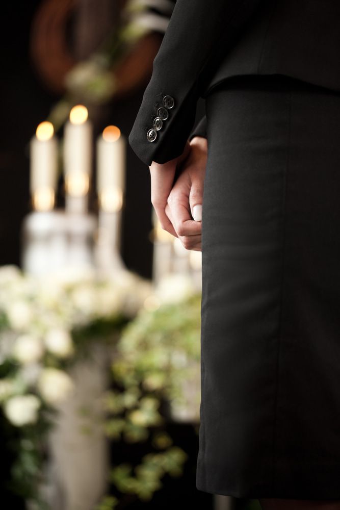 A Man in a Suit is Holding a Woman 's Hand at a Funeral — Bull Family Funerals in Moree, NSW