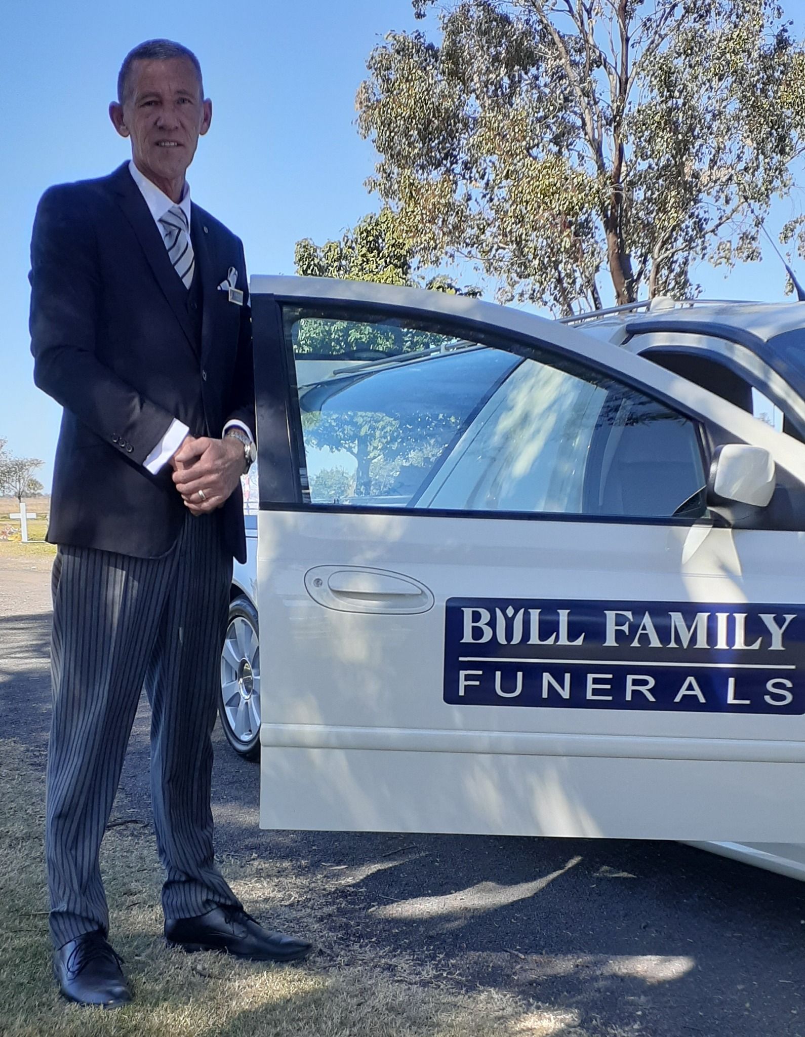 A Man is Holding a Urn With Flowers in a Funeral Home — Bull Family Funerals in Inglewood, QLD