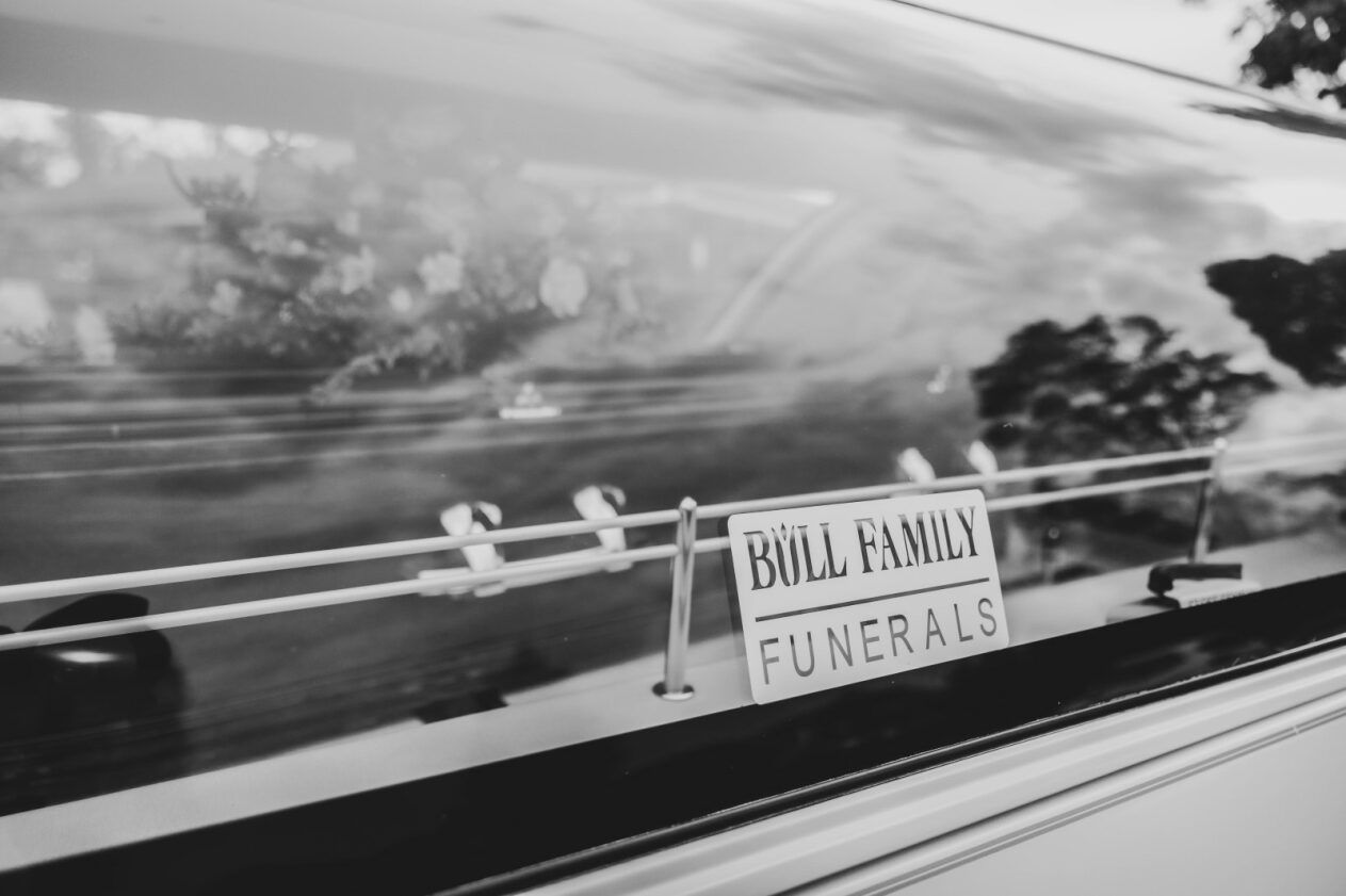 A Wooden Coffin With Flowers on Top of It in a Church — Bull Family Funerals in Inglewood, QLD