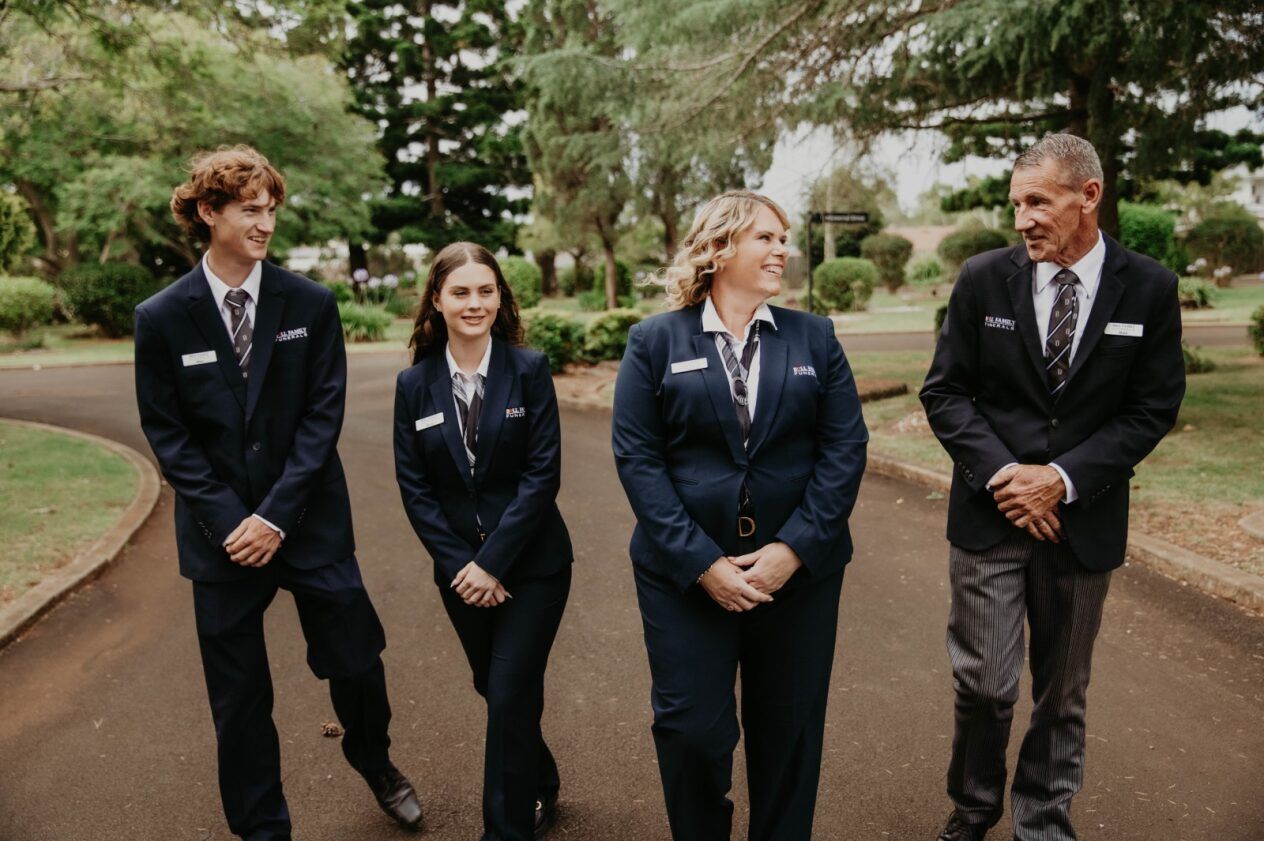 A Man and a Woman Are Sitting at a Table Holding a Metal Urn — Bull Family Funerals in Toowoomba, QLD