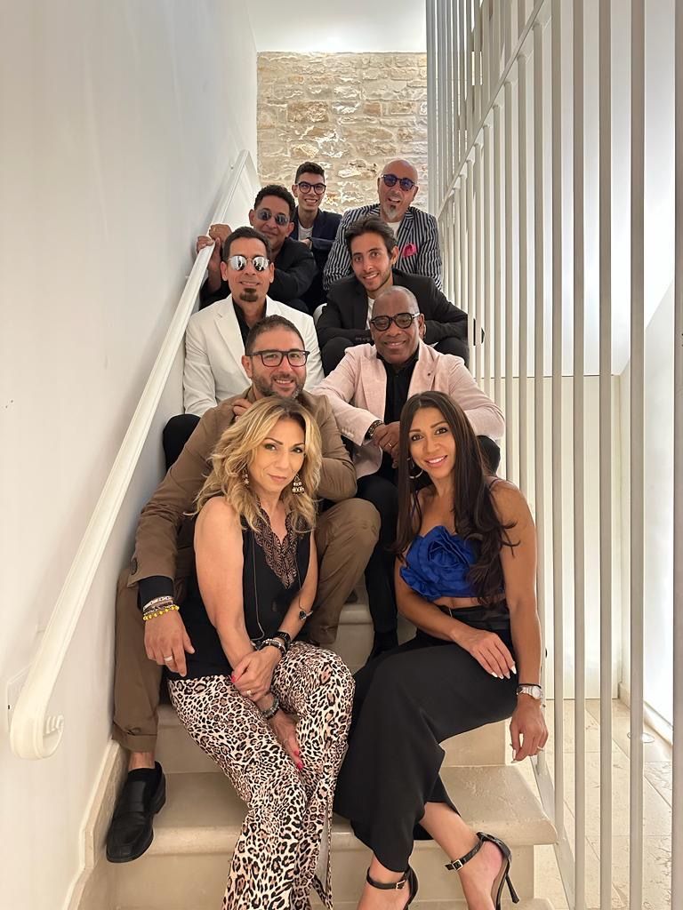 Gruppo di sette persone sedute su una scalinata, in posa insieme in abiti semi-formali.