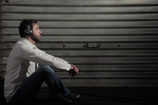 Il DJ, con le cuffie in testa, mixa musica su un giradischi sotto le luci viola del palco.