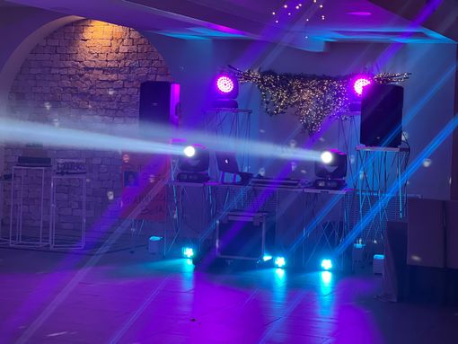 Persone che ballano durante un ricevimento formale in una sala da ballo, sotto le luci brillanti del palcoscenico.