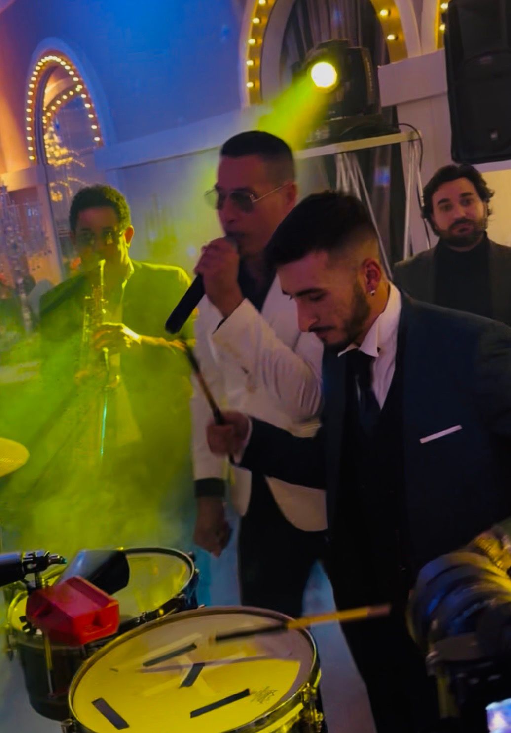 DJ mixa musica in una festa vivace, con gli ospiti che ballano sotto calde luci a catena e colorate luci di scena.