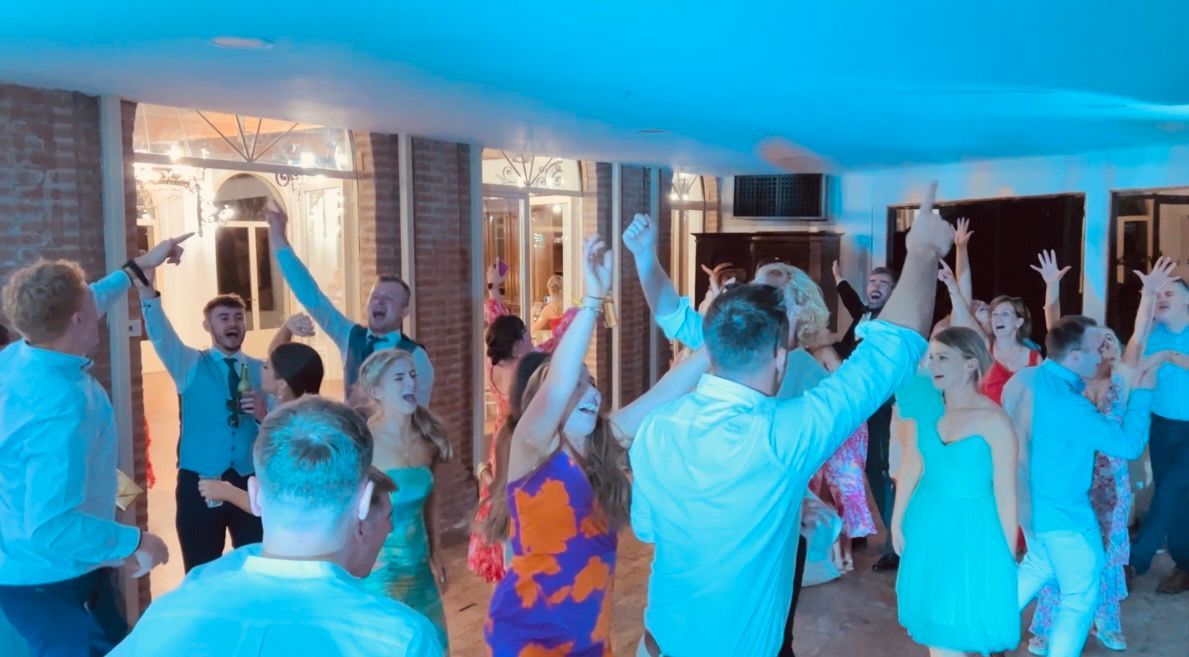 Un gruppo musicale si esibisce dal vivo sul palco mentre il pubblico alza le mani durante un concerto colorato.