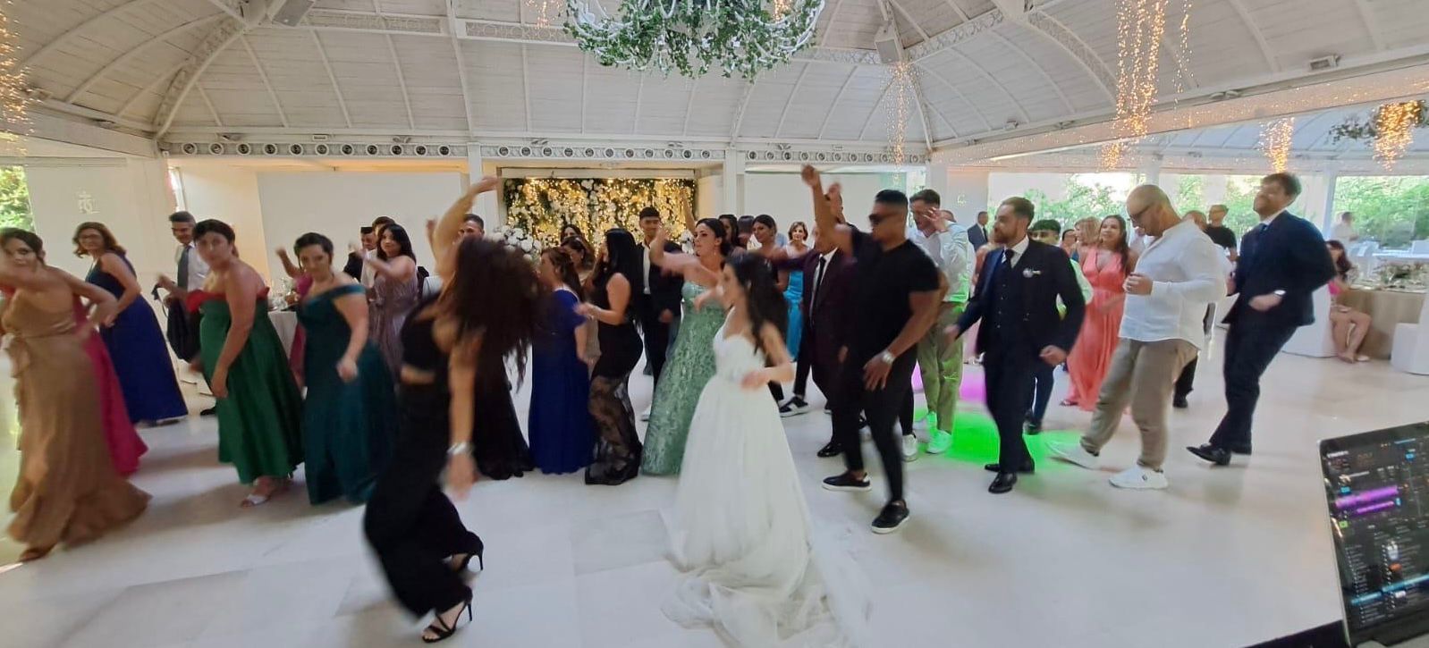 La sposa e gli invitati ballano a un luminoso ricevimento di nozze al chiuso con luci verdi.