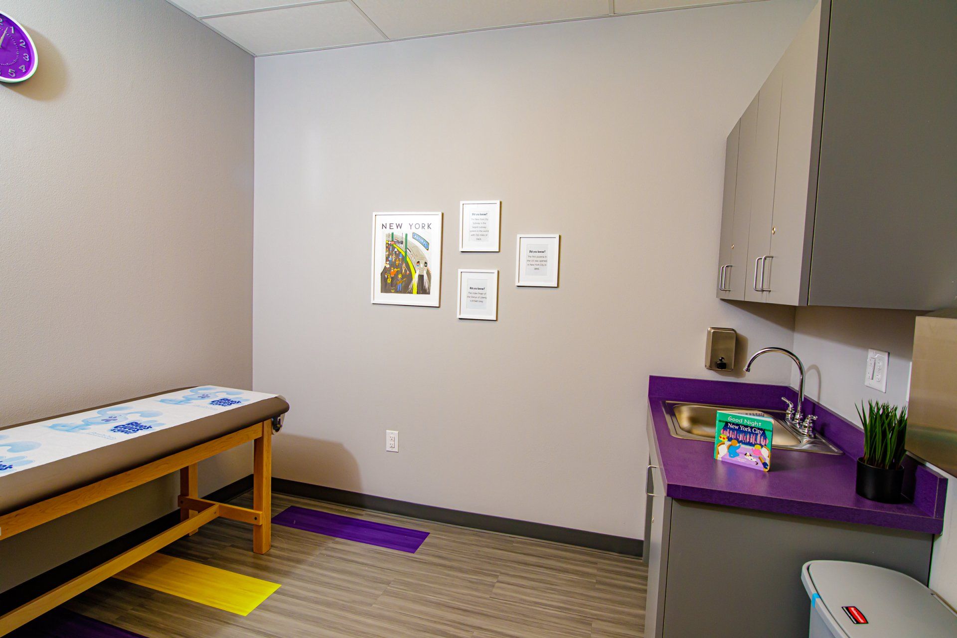 A doctor 's office with a purple counter and a purple table.