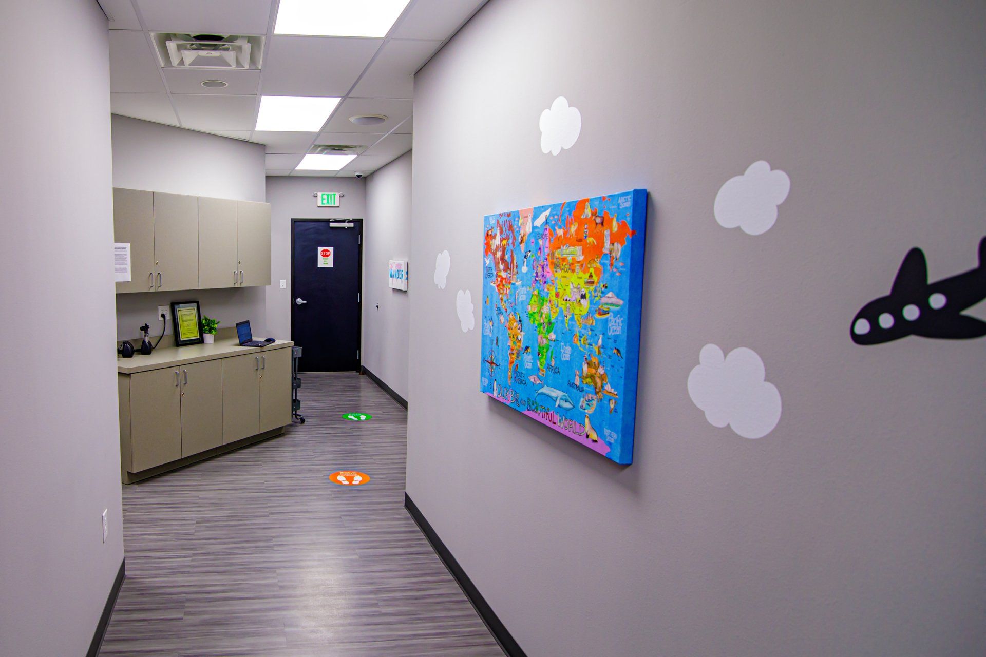 A hallway with a painting of an airplane and a map of the world on the wall.