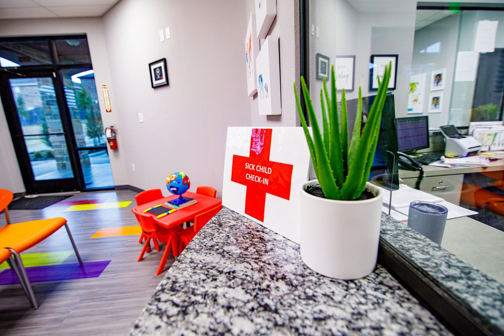 A potted plant is sitting on a counter next to a red cross sign.