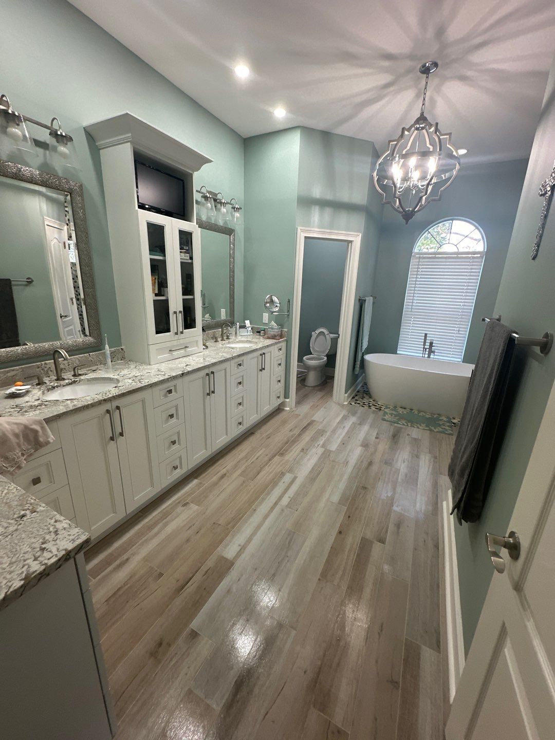 A bathroom with a tub , sink , toilet and mirror.