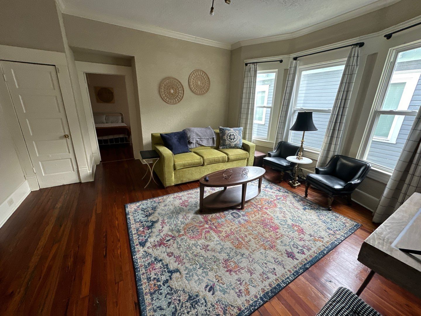 A living room with a couch , chairs , coffee table and rug.