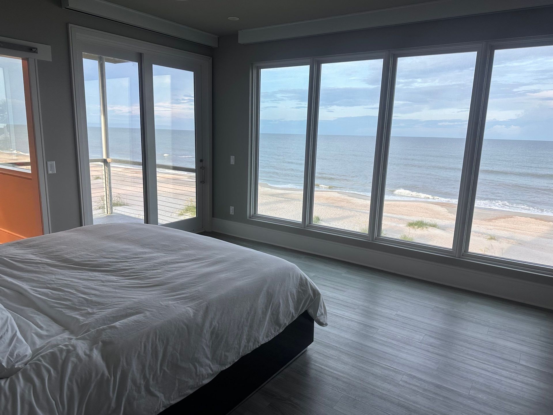 A bedroom with a large bed and lots of windows overlooking the ocean.