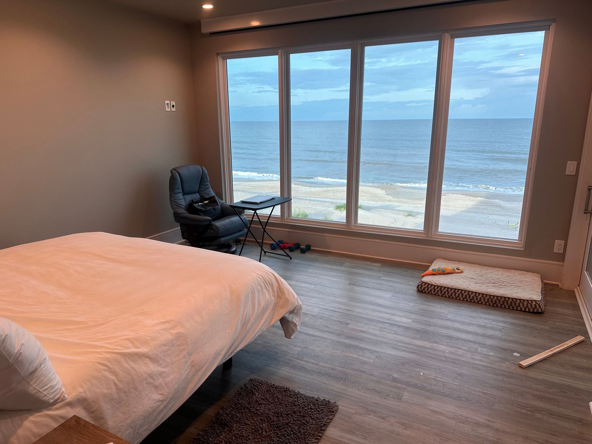 A bedroom with a large bed and a large window overlooking the ocean.