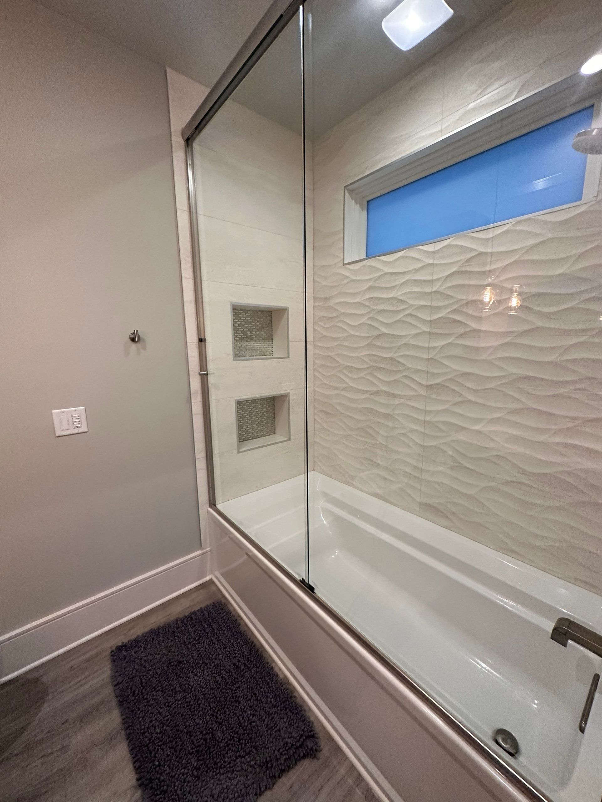 A bathroom with a bathtub and a shower with a glass door.