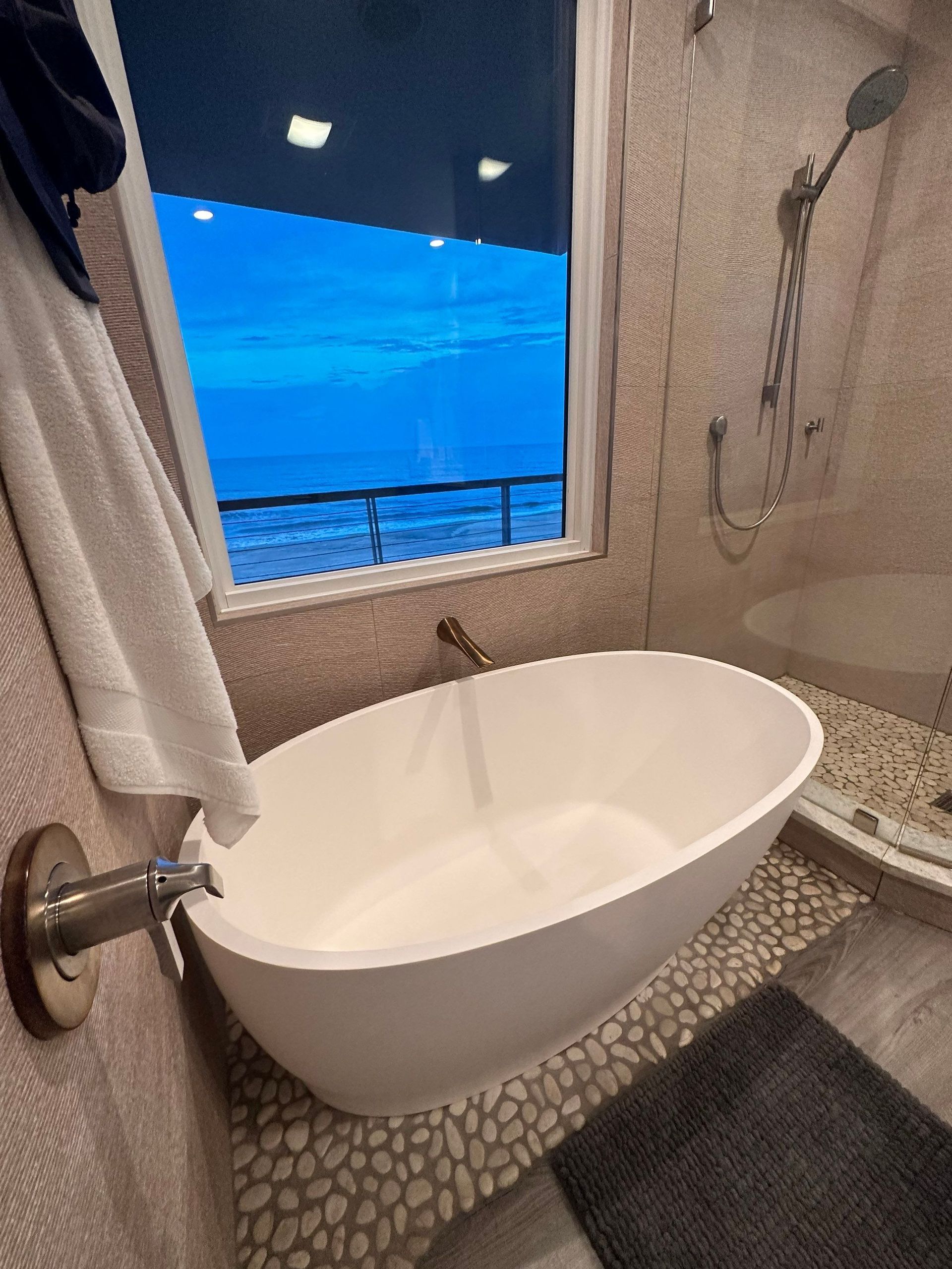 A bathroom with a bathtub , shower , and window.