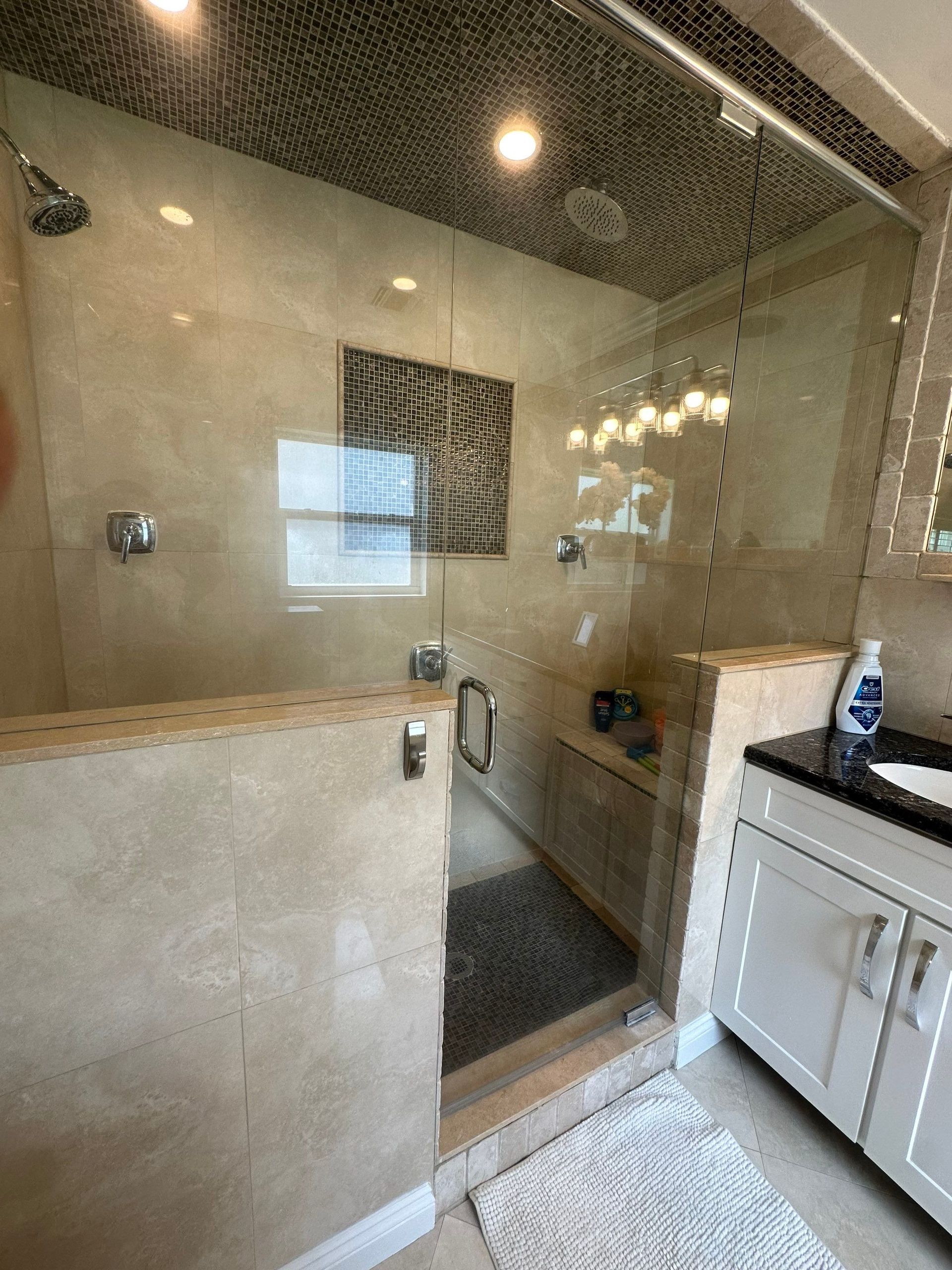 A bathroom with a walk in shower and a sink.