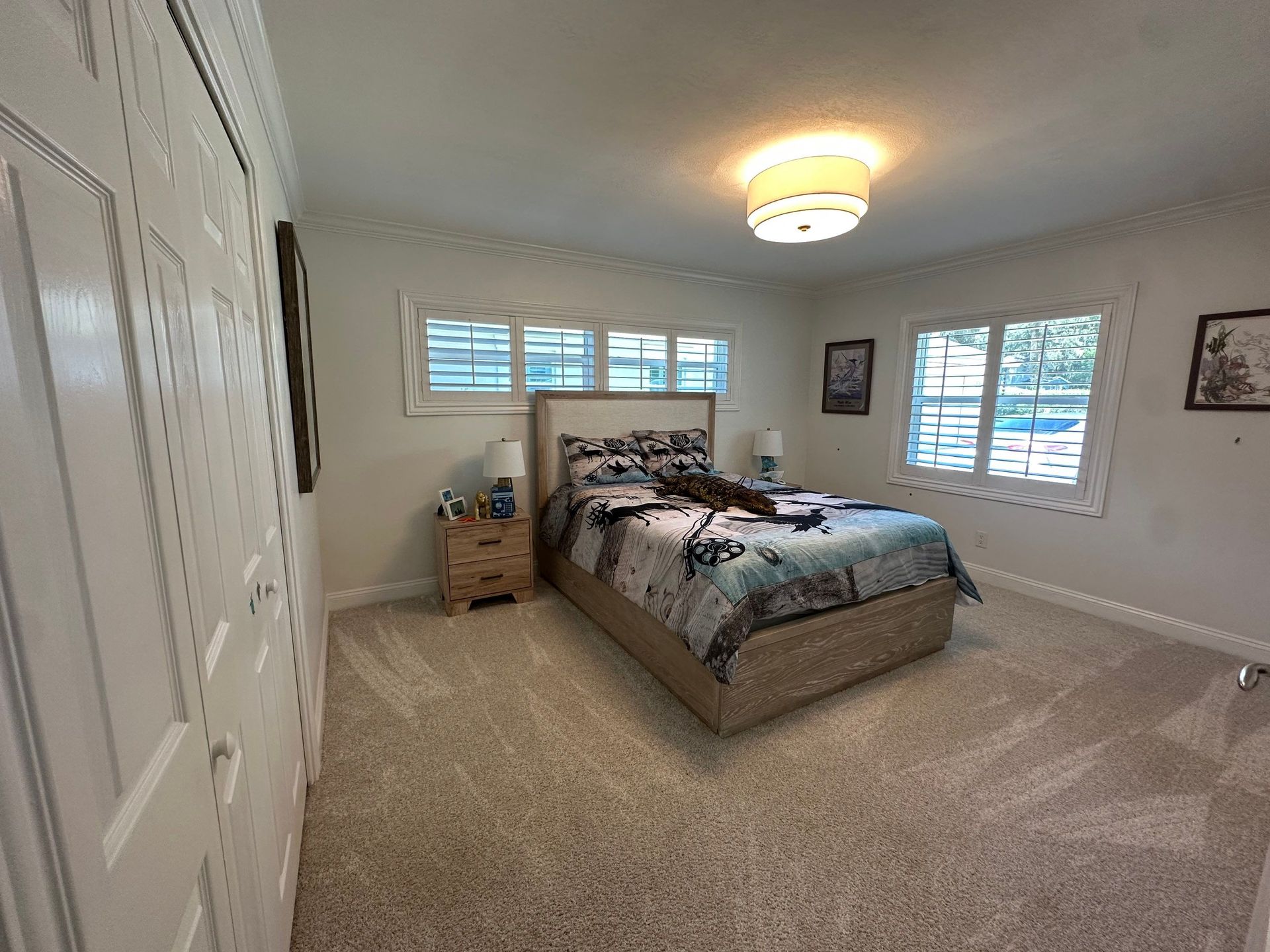 A bedroom with a bed , nightstand , and windows.