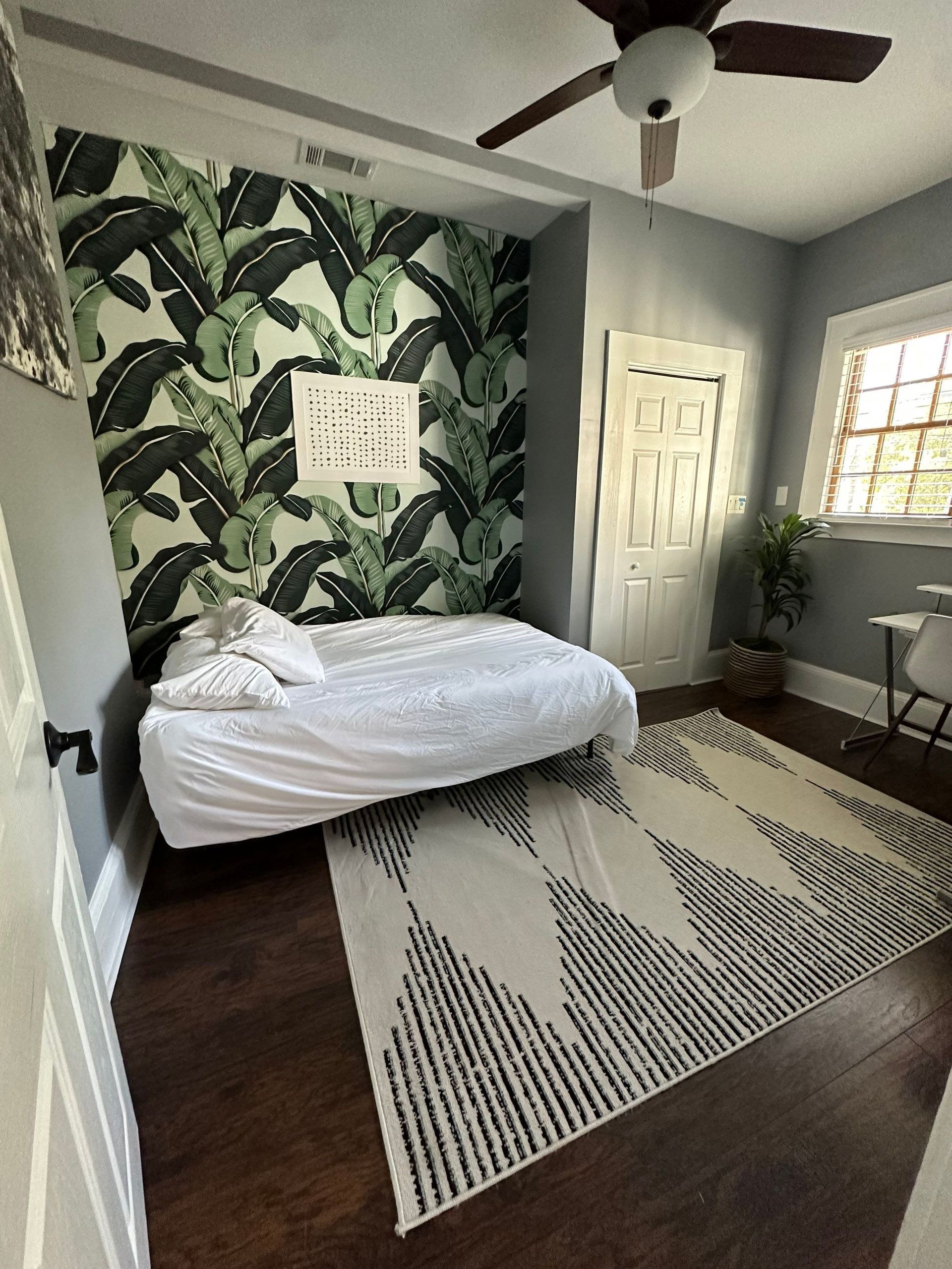 A bedroom with a bed , rug and ceiling fan.