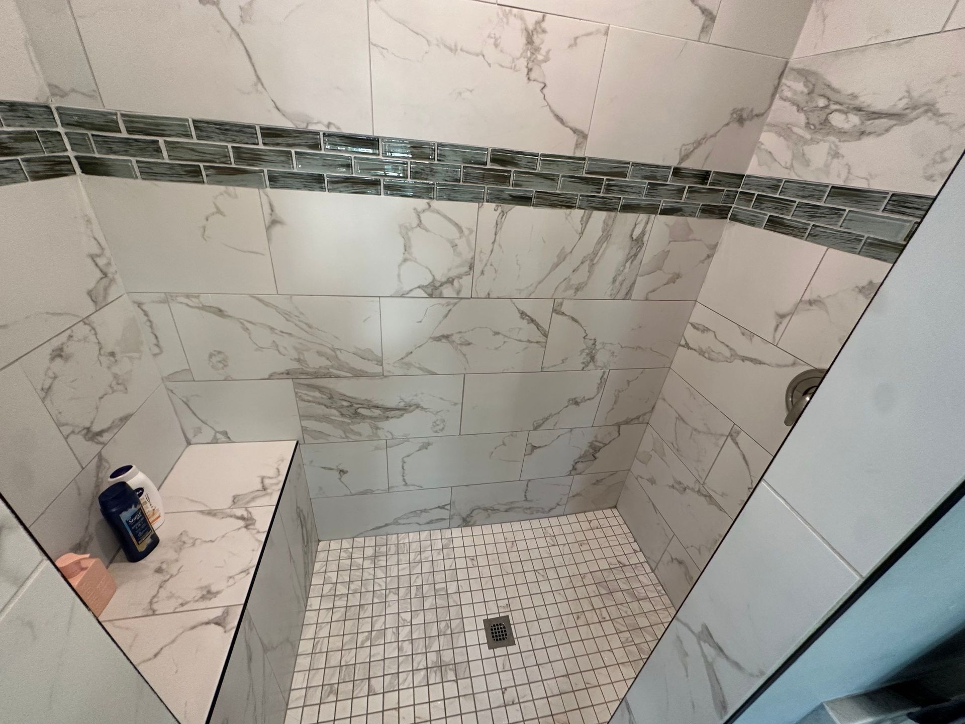 A bathroom with marble tiles and a walk in shower.