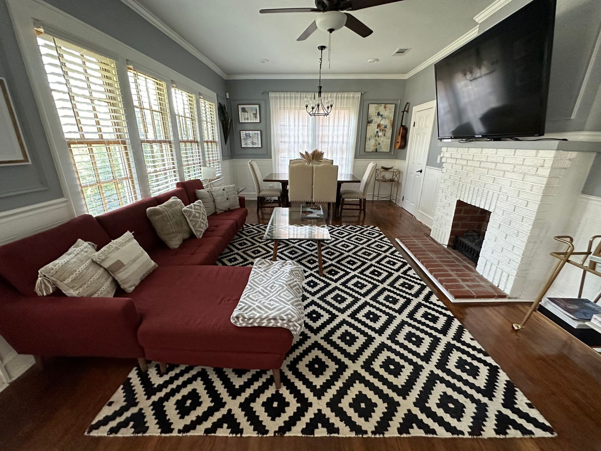 A living room with a red couch and a black and white rug.