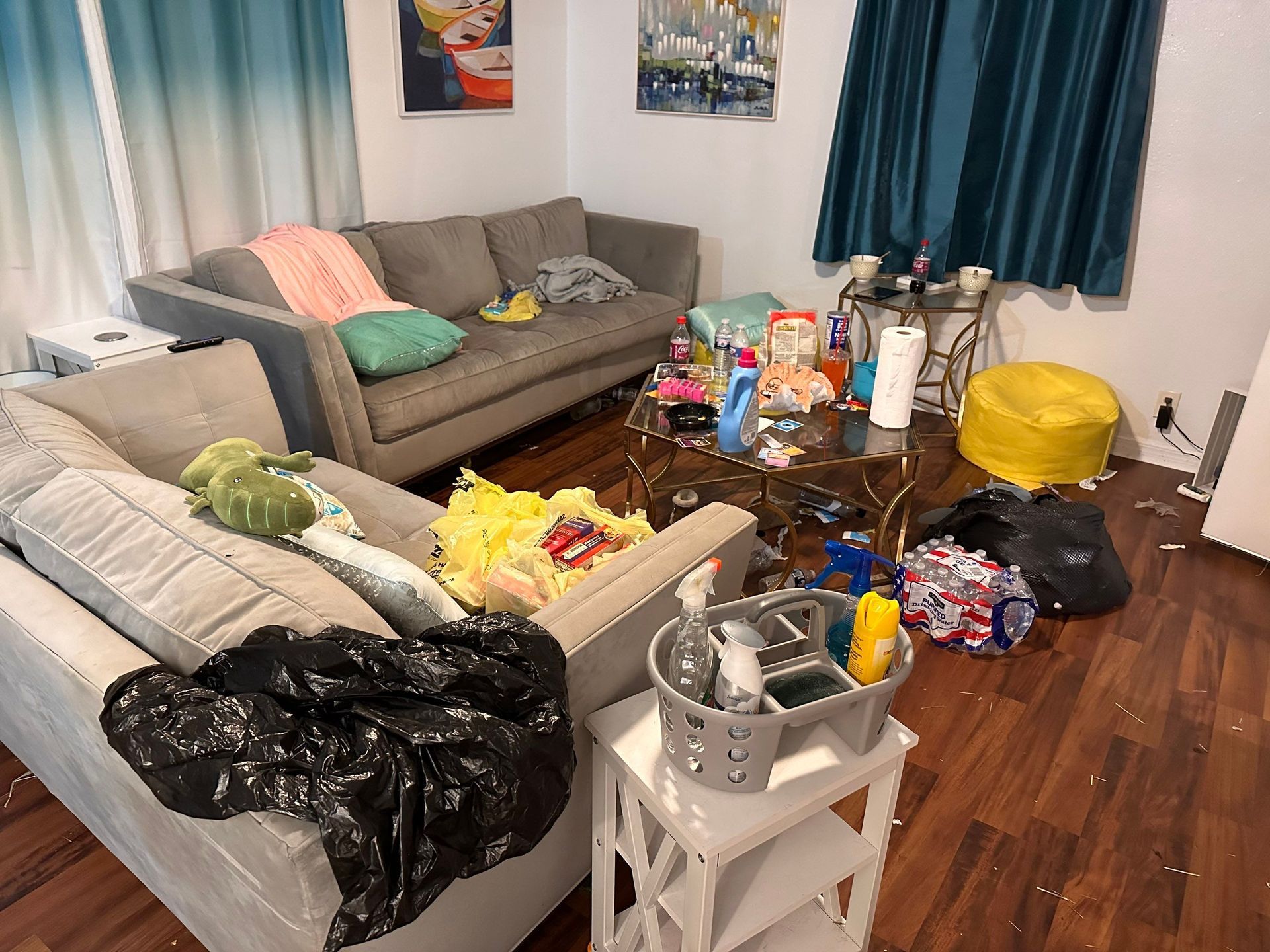 A living room with a couch and a table covered in trash.