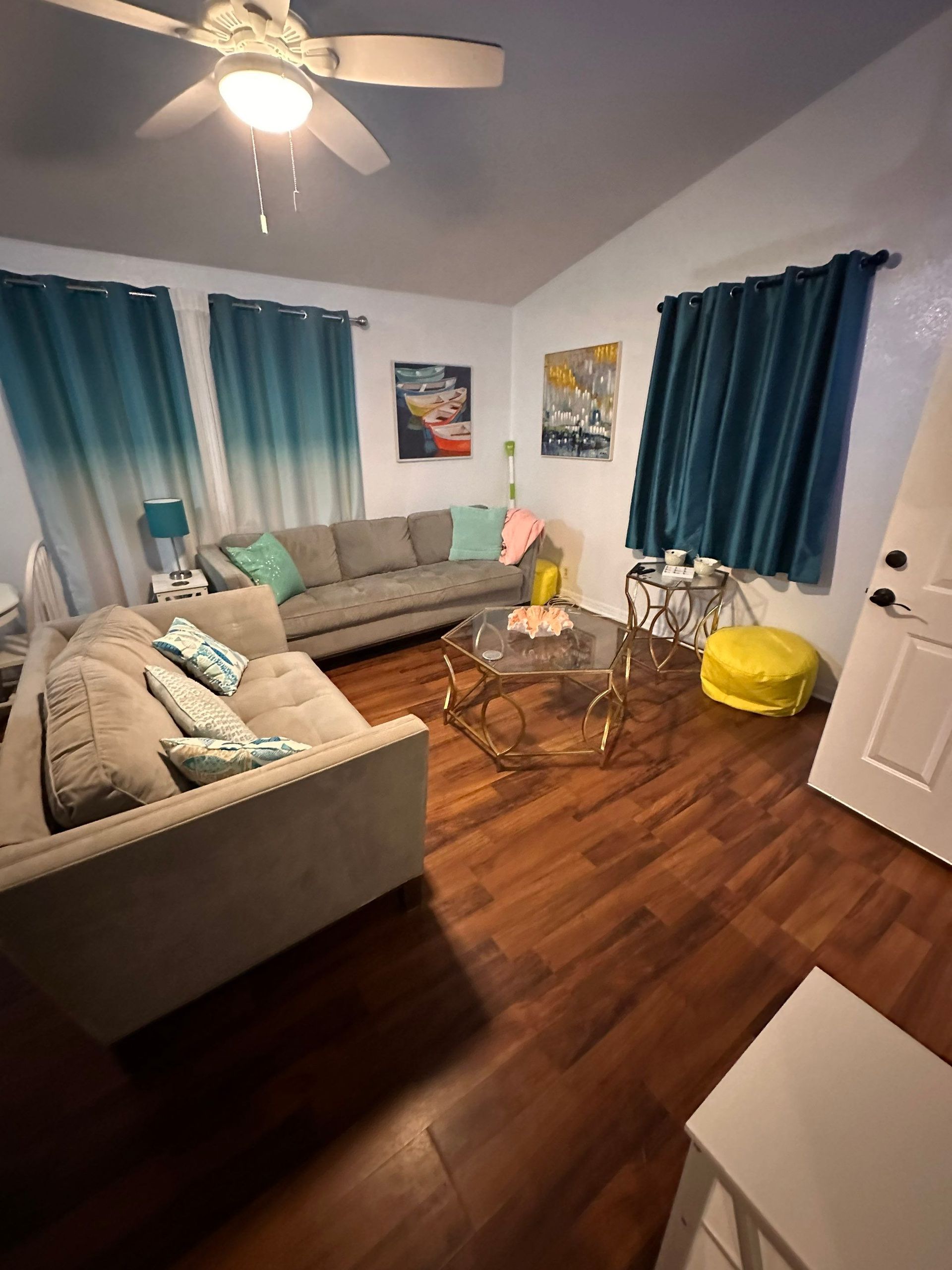 A living room with a couch , coffee table , and ceiling fan.