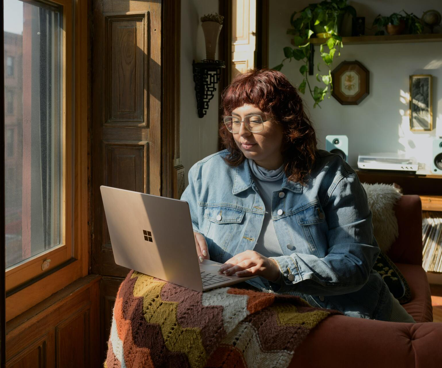 Mulher sentada em uma poltrona com um notebook em mãos estudando para o bootcamp online da XP Educação