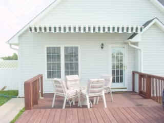 Residential Retractable Awning Installations — White House with Striped Awning in Spartanburg, SC