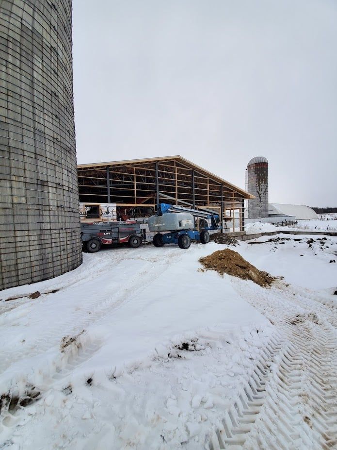 Un bâtiment en construction sous la neige avec un silo en arrière-plan. Construction en béton en Estrie.