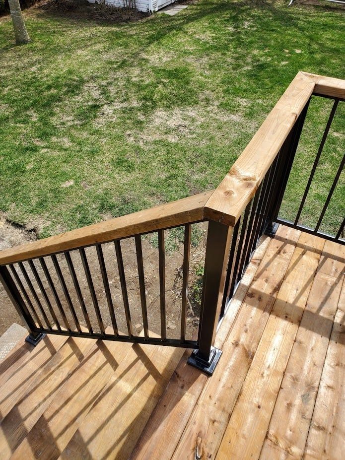 Une terrasse en bois avec escalier et garde-corps en métal.