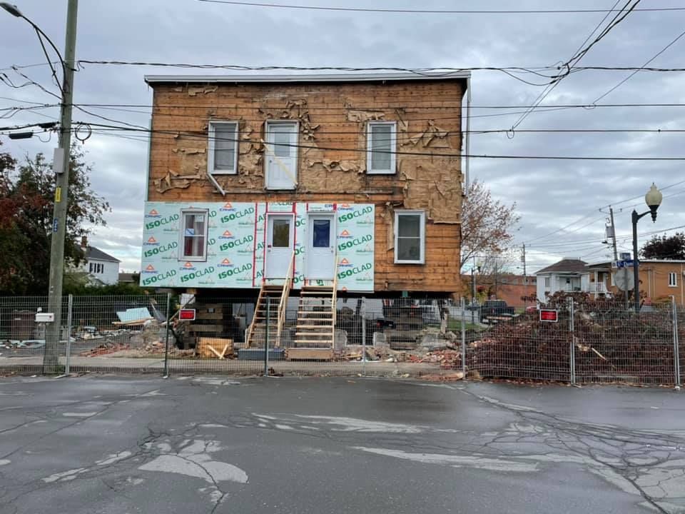 Un bâtiment est en construction sur pilotis au bord de la route. Levage de maison.