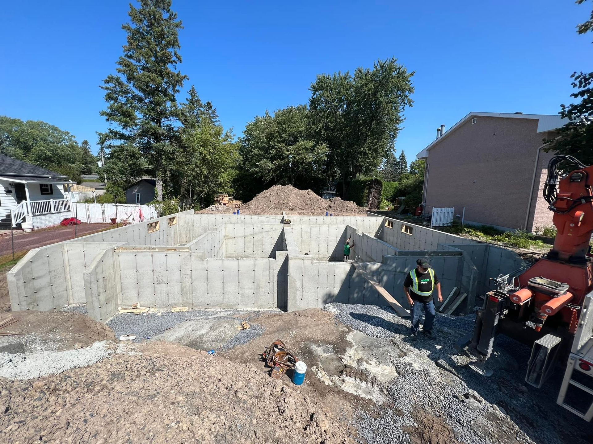 Un homme se tient devant une base en béton d'une maison en construction. Coffrage en béton pour fondation.