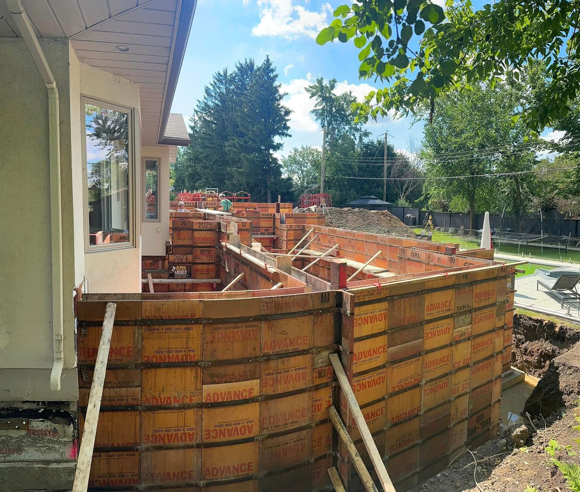 Un mur de béton est en construction devant une maison. Coffrage en béton.