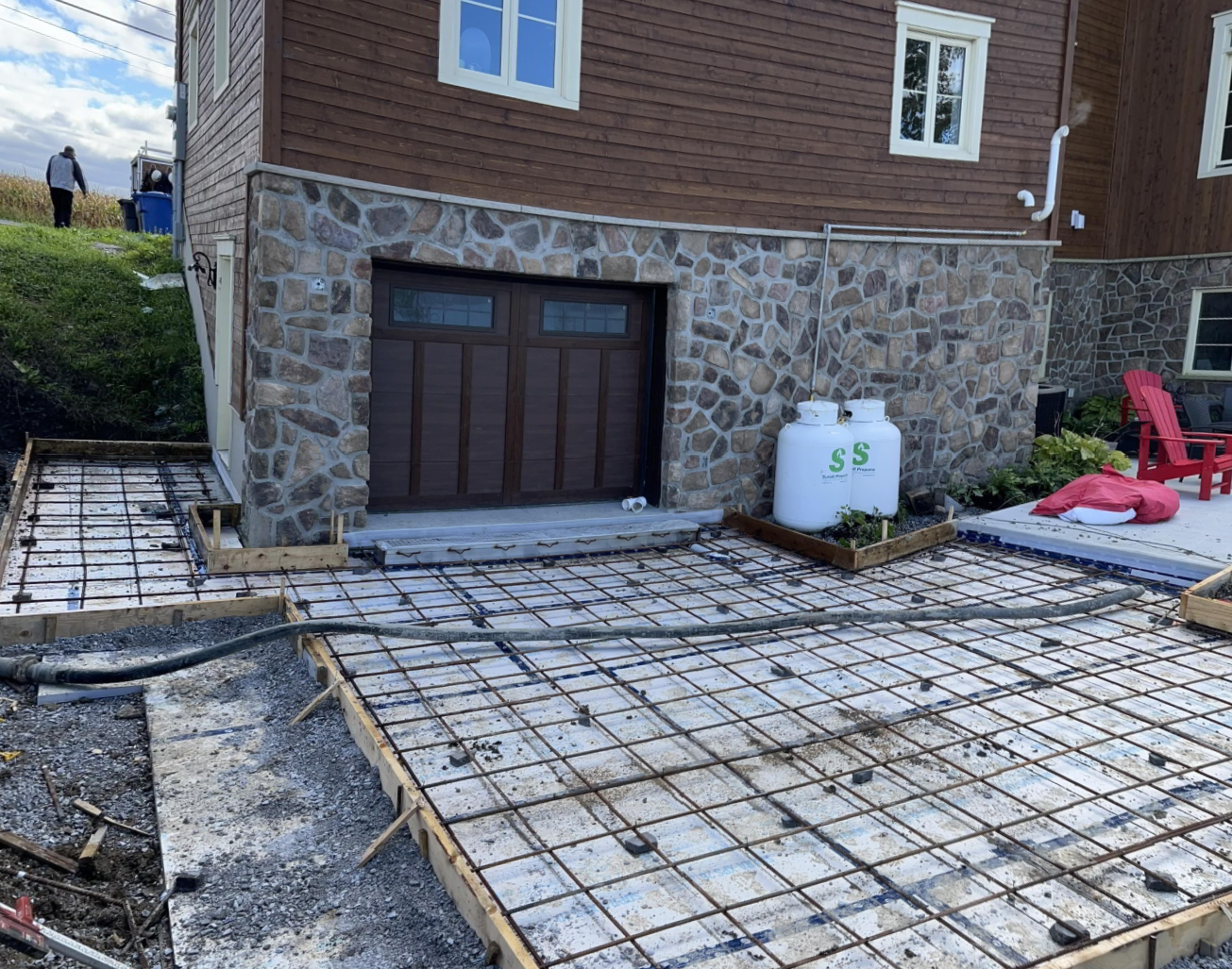 Un patio en béton est en cours de construction devant une maison.