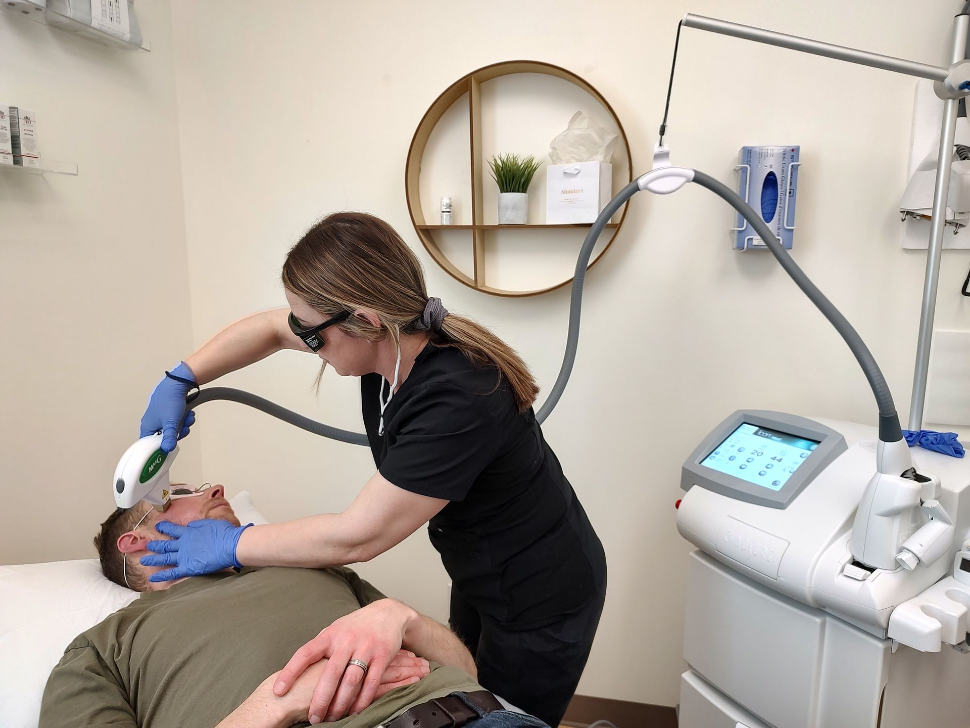 A woman is using a laser on a man 's face.