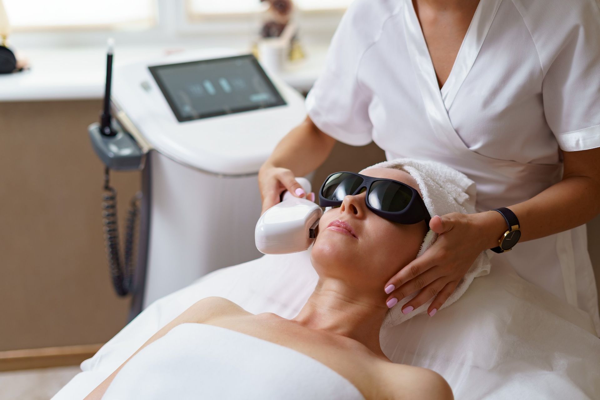 A woman is getting a laser treatment on her face in a beauty salon.