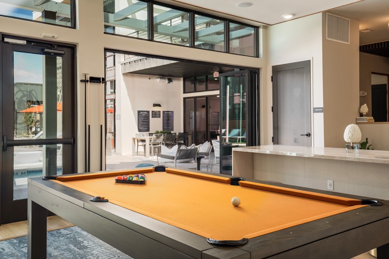 Indoor community recreation area with an orange pool table and lounge seating.