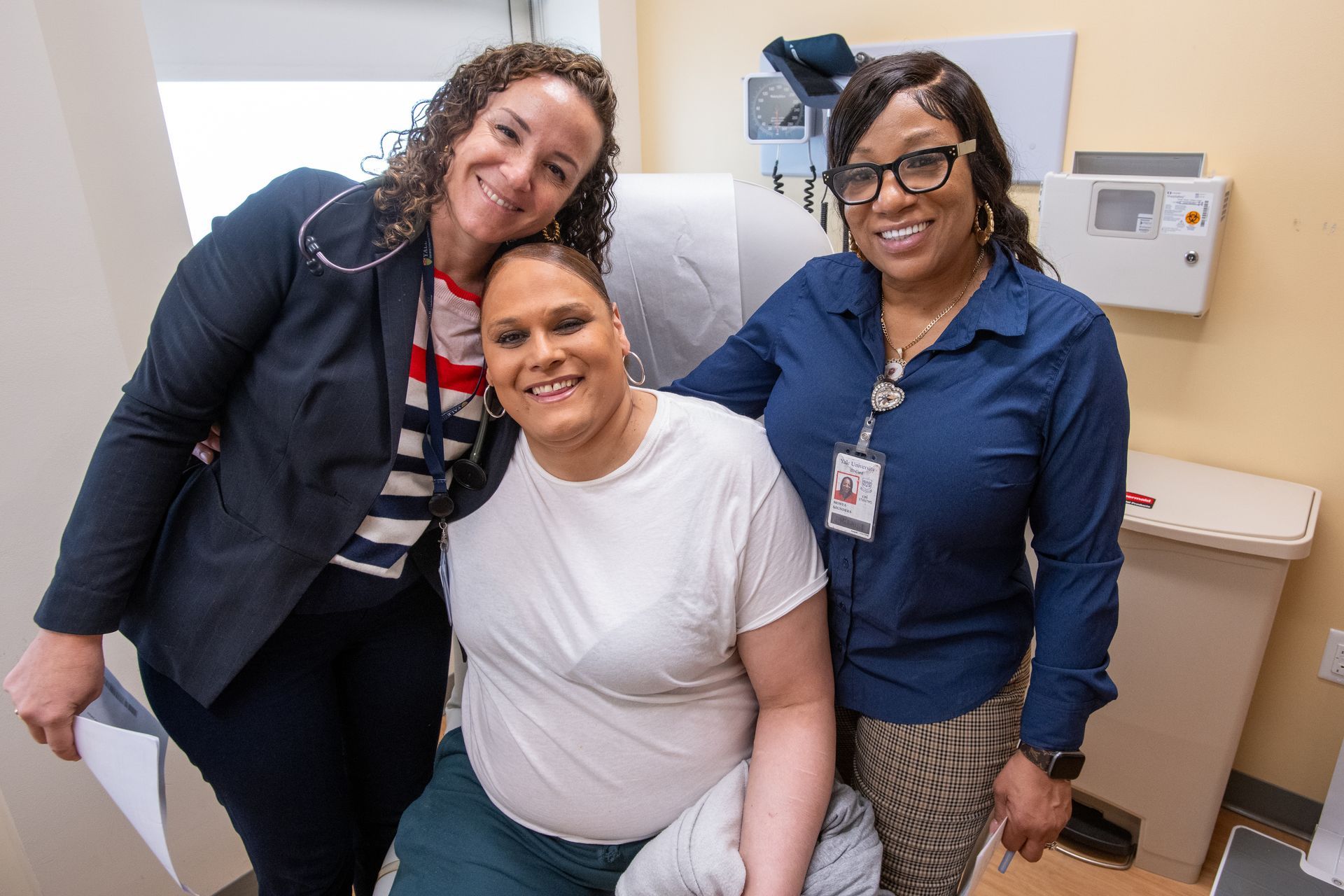 Three women are posing for a picture with a patient in a hospital room