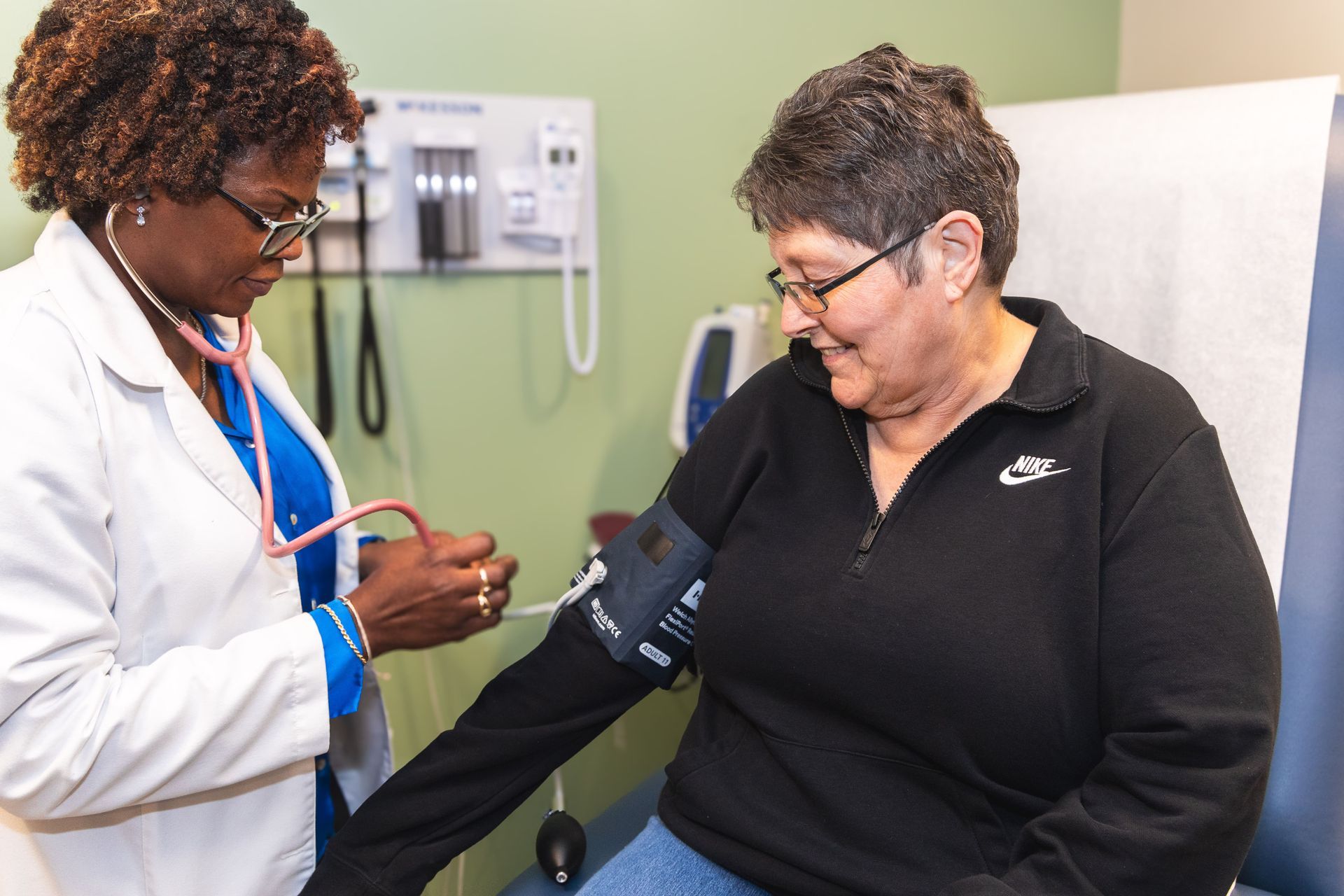 An image of a female doctor taking the blood pressure of a female patient