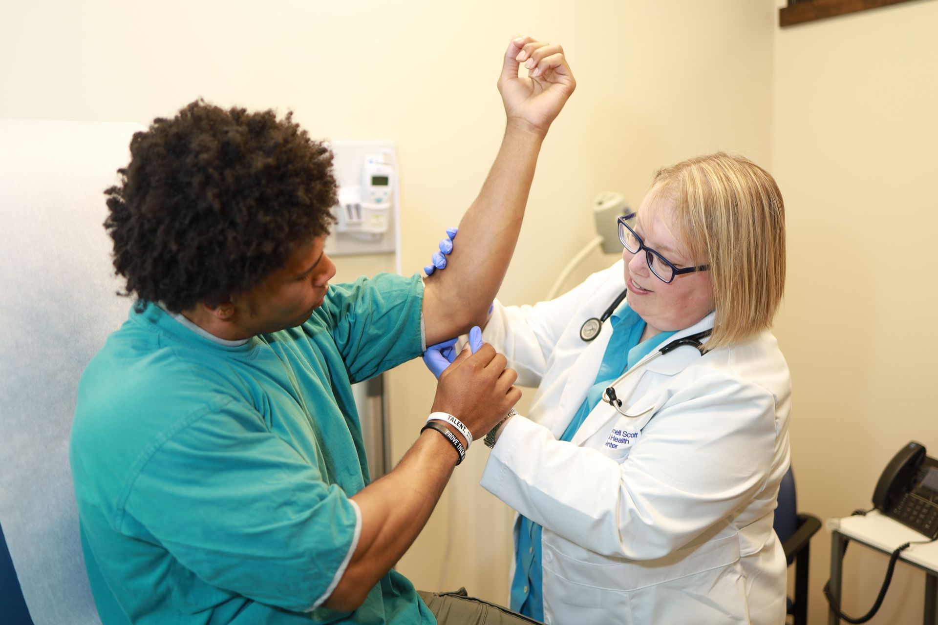 An image of a female doctor examining the elbow of a male patient
