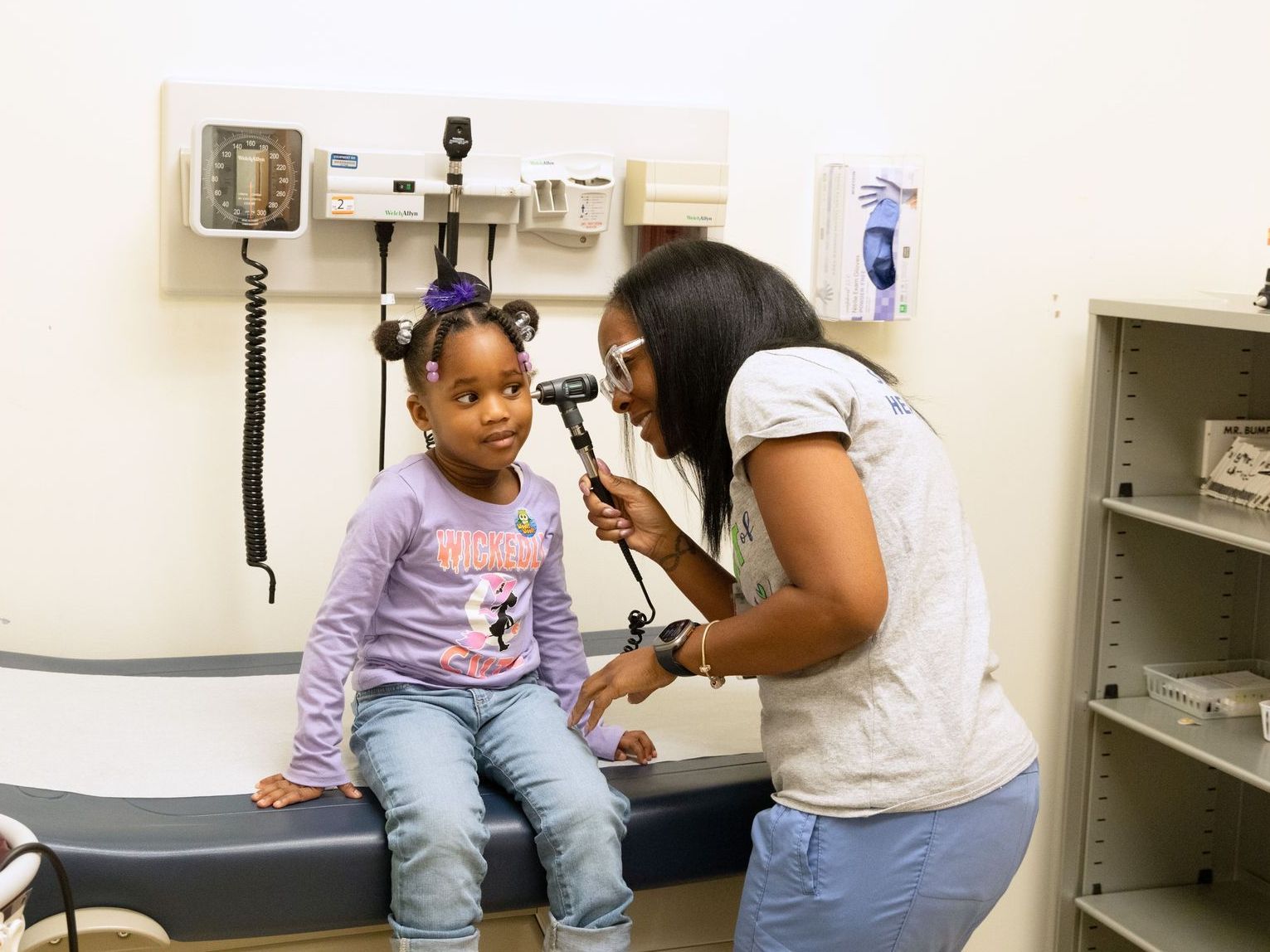 A woman is examining a little girl's ear with a stethoscope