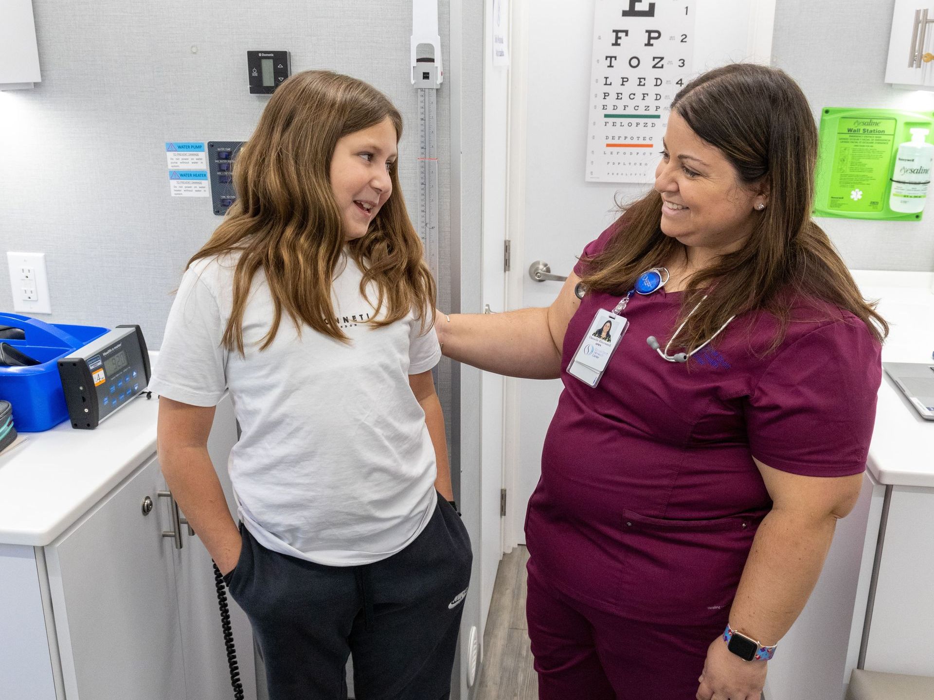 A nurse is talking to a young girl in a doctor's office