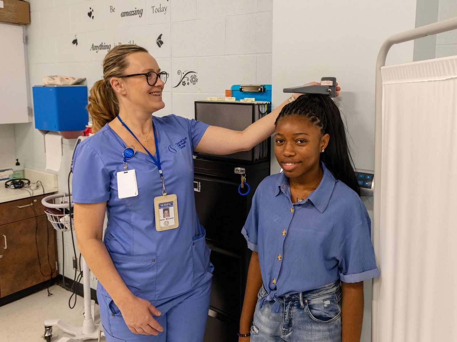 A nurse is measuring a girl's height in a hospital room