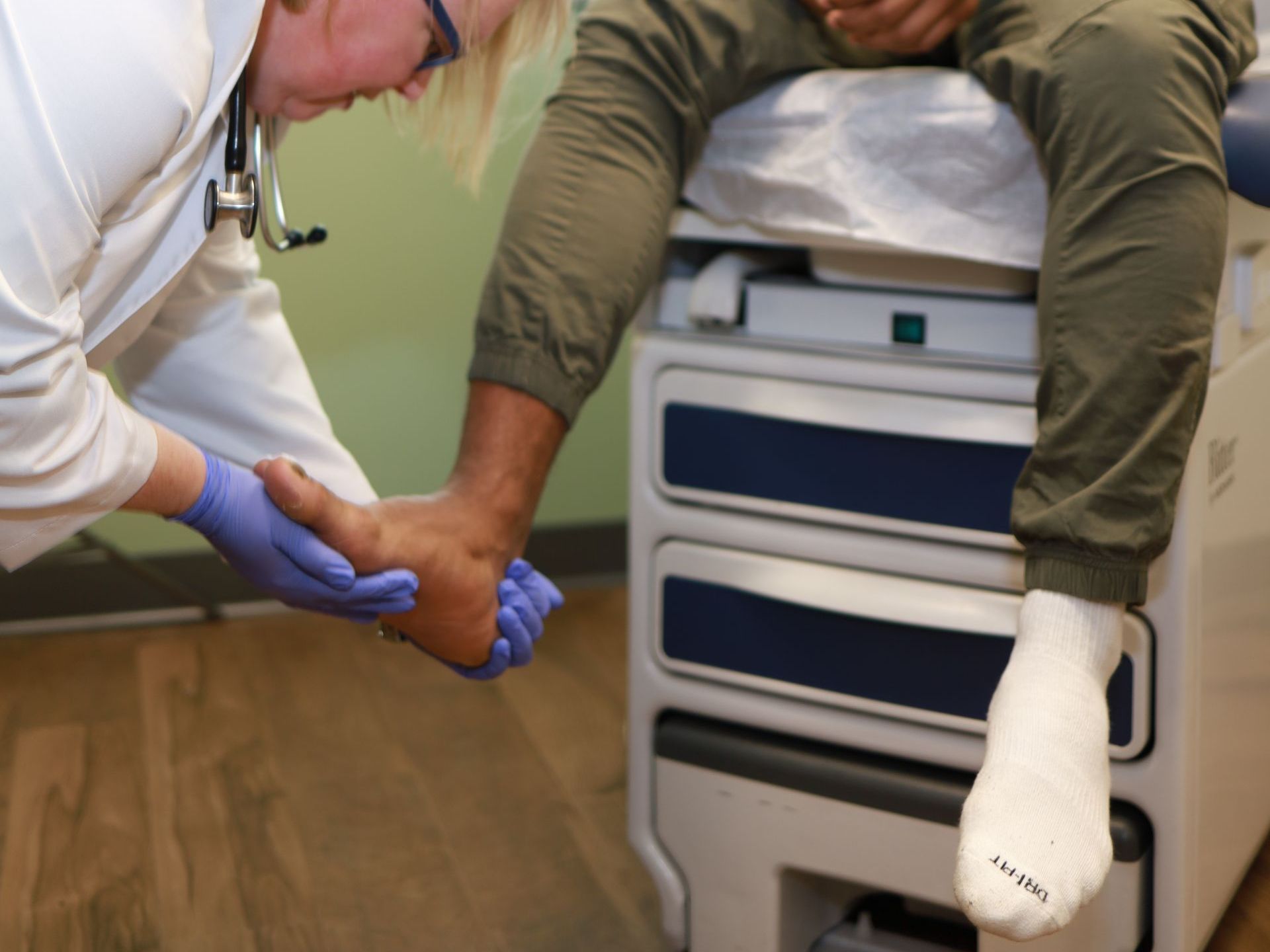 An image of a female doctor looking at the foot of a male patient