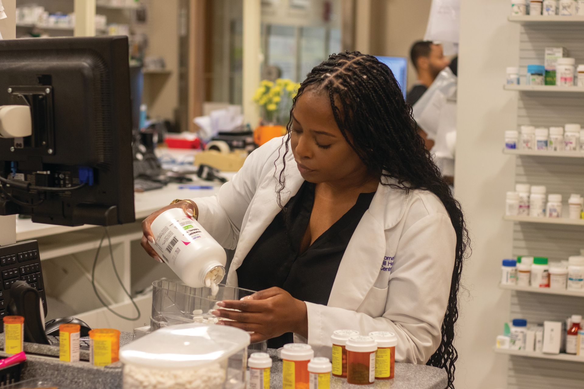 A female pharmacist is pouring pills into a container in a pharmacy