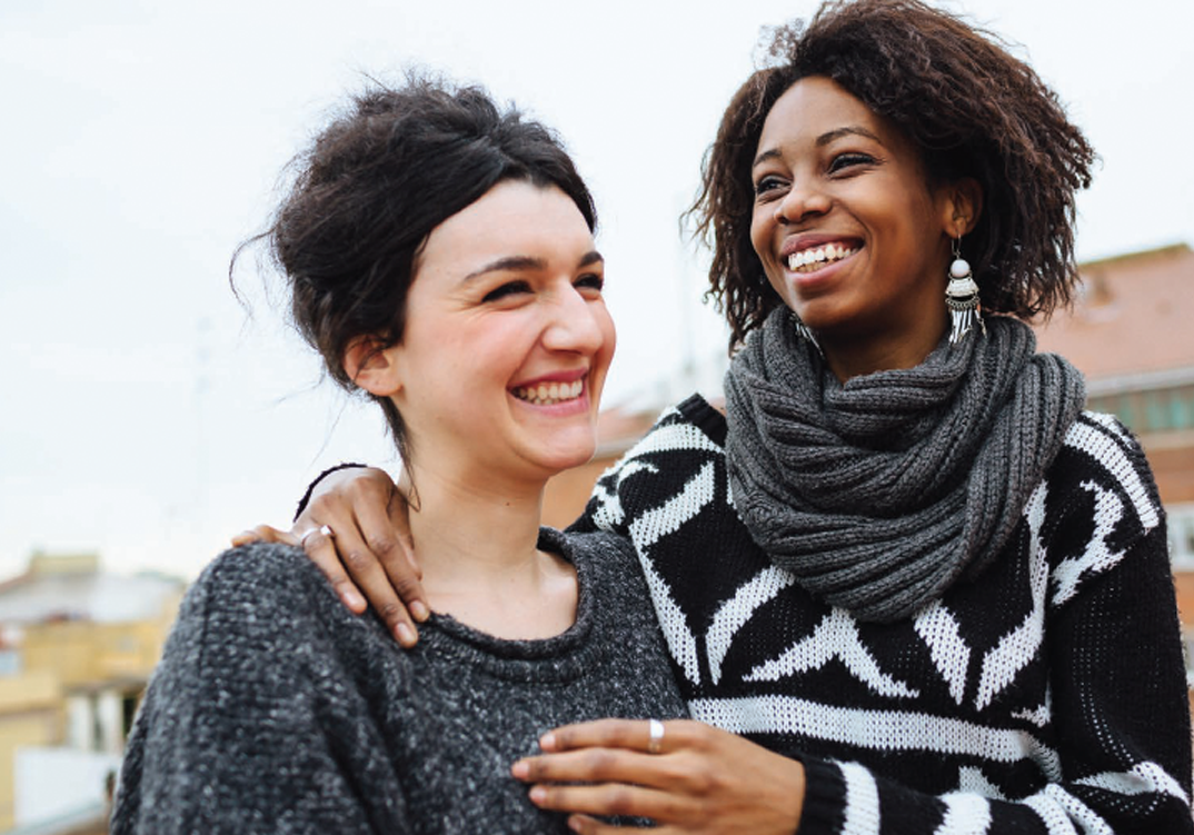 Two women smiling and embracing each other.
