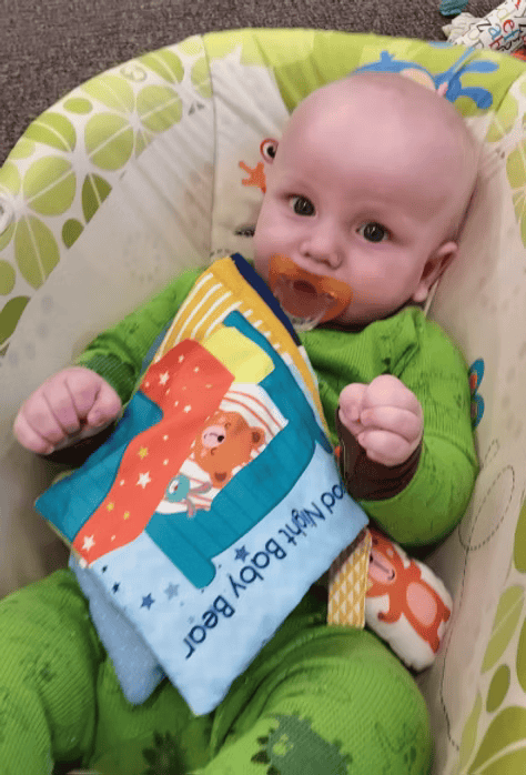 Baby in green onesie, holding a 