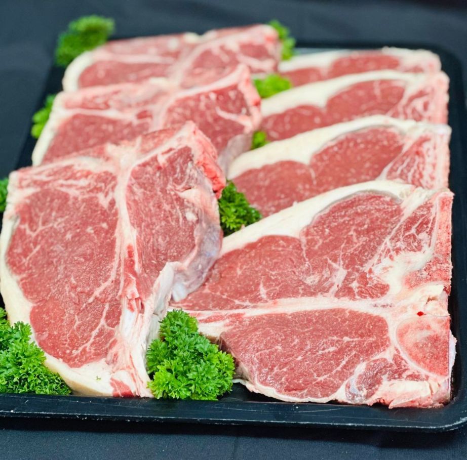 A Black Tray Filled With Raw Lamb Chops and Parsley — MC Butchery in Moranbah, QLD
