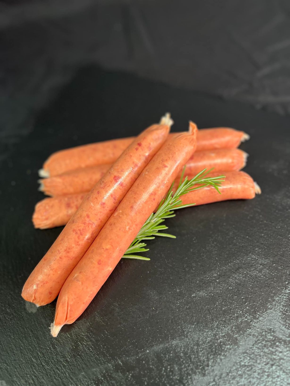 A Bunch Of Sausages Sitting On Top Of Each Other On A Black Surface — MC Butchery in Moranbah, QLD