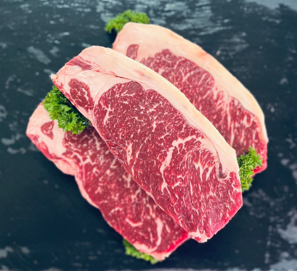 Three Raw Steaks Are Sitting On Top Of Each Other On A Black Surface — MC Butchery in Moranbah, QLD
